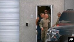 This frame grab from video provided by WPLG-TV shows FBI agents escorting Cesar Sayoc, in sleeveless shirt, in Miramar, Florida, on Oct. 26, 2018.
