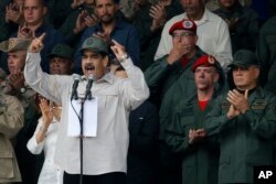 FILE - In this April 13, 2019 file photo, Venezuela's President Nicolas Maduro, speaks flanked by Defense Minister Vladimir Padrino Lopez, right, and Gen. Ivan Hernandez, second from right, head of both the presidential guard and military counterintelligence in Caracas, Venezuela, April 13, 2019.