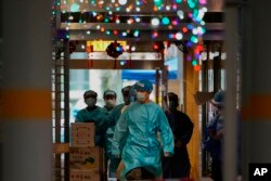 Petugas kesehatan dengan APD berjalan di Kwai Chung Estate, di Hong Kong, Sabtu, 22 Januari 2022. (Foto: AP)