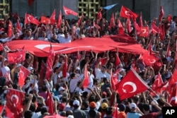 Turkish citizens wave their national flags as they protest against the military coup outside Turkey's parliament in Ankara, July 16, 2016.