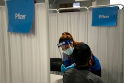 FILE - A nurse administers the Pfizer COVID-19 vaccine to a patient at Providence Edwards Lifesciences vaccination site in Santa Ana, California, May 21, 2021,
