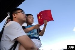 Foto yang diambil pada 6 September 2018 menunjukkan seorang pria menggendong anaknya di sebuah taman di Beijing. China bersiap untuk menghapus kebijakan dua anaknya.