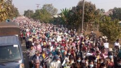 In this image provided by the Military True News Information Team, supporters of the military government hold miniature Myanmar flags as they march during a rally on Feb. 1, 2022, in Naypyitaw, Myanmar.