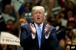 Republican presidential candidate Donald Trump applauds after singing the National Anthem during a rally at the Anaheim Convention Center, Wednesday, May 25, 2016.