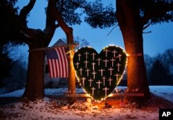 FILE - A makeshift memorial with crosses for the victims of the Sandy Hook Elementary School shooting massacre stands outside a home in Newtown, Conn., on the one-year anniversary of the shootings, Dec. 14, 2013.