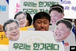 An activist with cutouts of South Korean President Moon Jae-in, left, and North Korean leader Kim Jong Un participates in a rally welcoming the planned summit between South and North Korea in Seoul, South Korea, Apr. 25, 2018.