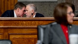 Sen. Mark Warner, D-Va., left, and Sen. Thom Tillis, R-N.C., center, speak together as Treasury Secretary Janet Yellen and Federal Reserve Chairman Jerome Powell testify during a Senate Banking Committee hearing on Capitol Hill, Nov. 30, 2021.