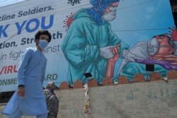 Papan bergambar petugas medis dan ucapan terima kasih atas pengabdian mereka dalam penanganan Covid-19 di Rawalpindi, 30 Juni 2020.