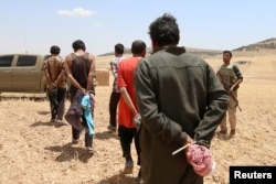Men, who the Democratic Forces of Syria fighters claimed were Islamic State fighters, walk as they are taken prisoners after SDF advanced in the southern rural area of Manbij, in Aleppo Governorate, Syria, May 31, 2016.