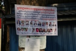 A poster plastered on a tree displays 18 senior CNRP leaders wanted for arrest in Poipet, Banteay Meanchey province, on Nov 7, 2019. (Sun Narin/VOA Khmer)