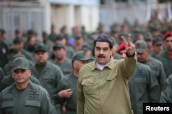 រូបឯកសារ៖ លោក Nicolas Maduro ប្រធានាធិបតីវ៉េណេស៊ុយអេឡា លើកដៃនៅក្នុងកិច្ចប្រជុំមួយជាមួយកងទ័ពយោធា​នៅឯមូលដ្ឋានយោធាមួយកន្លែងនៅក្នុងទីក្រុង Caracas ប្រទេសវ៉េណេស៊ុយអេឡា កាលពីថ្ងៃទី៣០ ខែមករា ឆ្នាំ២០១៩។