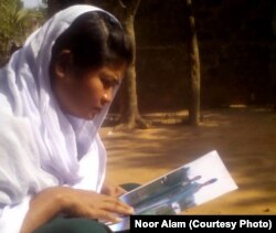 Ruksha Khan holds a photo of her husband, Hanif Khan, in front of her house in Kashipur village of Assam state in India, Jan. 12, 2018.