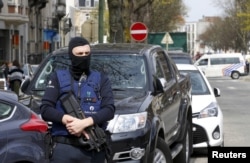 FILE - Belgium police officers secure the access during a police operation in Etterbeek, near Brussels, Belgium, April 9, 2016.