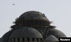 Workers are seen on top of a mosque as a warplane flies past in the southeastern city of Diyarbakir, Turkey, March 20, 2018.