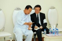FILE - Cambodian Prime Minister Hun Sen, left, talks with dissolved main opposition Cambodia National Rescue Party leader Kem Sokha at the mourning ceremony for Sen's mother in-law, in Phnom Penh, Cambodia, May 5, 2020.