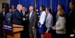 Republican presidential candidate Donald Trump, right, greets some of the 22 delegates from North Dakota to the Republican National Convention, who are the core of delegates that elevated Trump over the 1,237 needed for the GOP's presidential nomination in Bismarck, North Dakota, May 26, 2016.