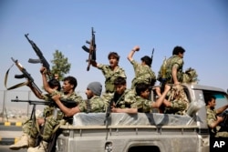 FILE - Shi'ite fighters, known as Houthis, ride on a patrol truck as they chant slogans during a tribal gathering showing support for the Houthi movement in Sana'a, Yemen.