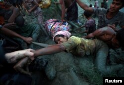 FILE - Photographers help a Rohingya refugee out of the Nad River as they cross the Myanmar-Bangladesh border in Palong Khali, near Cox's Bazar, Bangladesh, Nov. 1, 2017.