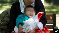 A child is wrapped up against the cold at a park in Beijing, China, Oct. 30, 2015. Shares of companies making diapers, baby strollers and infant formula got a boost Friday from China's decision to scrap its one-child policy.