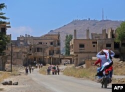 FILE - An Israeli military intelligence base (background) is pictured as Syrians return to the town of Quneitra in the Syrian Golan Heights, July 27, 2018.