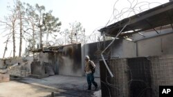 An Afghan security personnel walks at the gate of the German consulate in Mazar-i-Sharif, capital of northern Balkh province, Afghanistan, Friday, Nov. 11, 2016. The consulate was attacked by a suicide car bomber who rammed the compound.