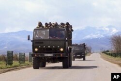 FILE - Ethnic Armenian fighters stand in backs of Kamaz military trucks on their way to a frontline at Martakert province in the separatist region of Nagorno-Karabakh, Azerbaijan, Monday, April 4, 2016.