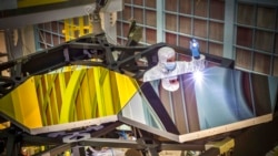 Un ingénieur optique examine deux segments de miroir sur un prototype du télescope spatial James Webb au Centre Spatial Goddard à Greenbelt, dans le Maryland, le 29 septembre 2014.