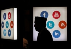 Seorang delegasi pertemuan Bank Pembangunan Islam (Islamic Development Bank/IDB) berjalan di depan logo-logo media sosial di Jakarta Convention Center, Jakarta, 16 Mei 2016. (Foto: Reuters)