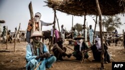 Un pasteur Fulani et son fils portant un turban attendent les transactions de bétail au marché aux bestiaux d'Illiea, dans l'État de Sokoto, au Nigéria, le 21 avril 2019.