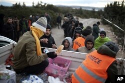 FILE - Migrants queue to get free food as they wait to travel to Greek islands by dinghies, near Cesme, Izmir, Turkey, Dec. 31, 2015.