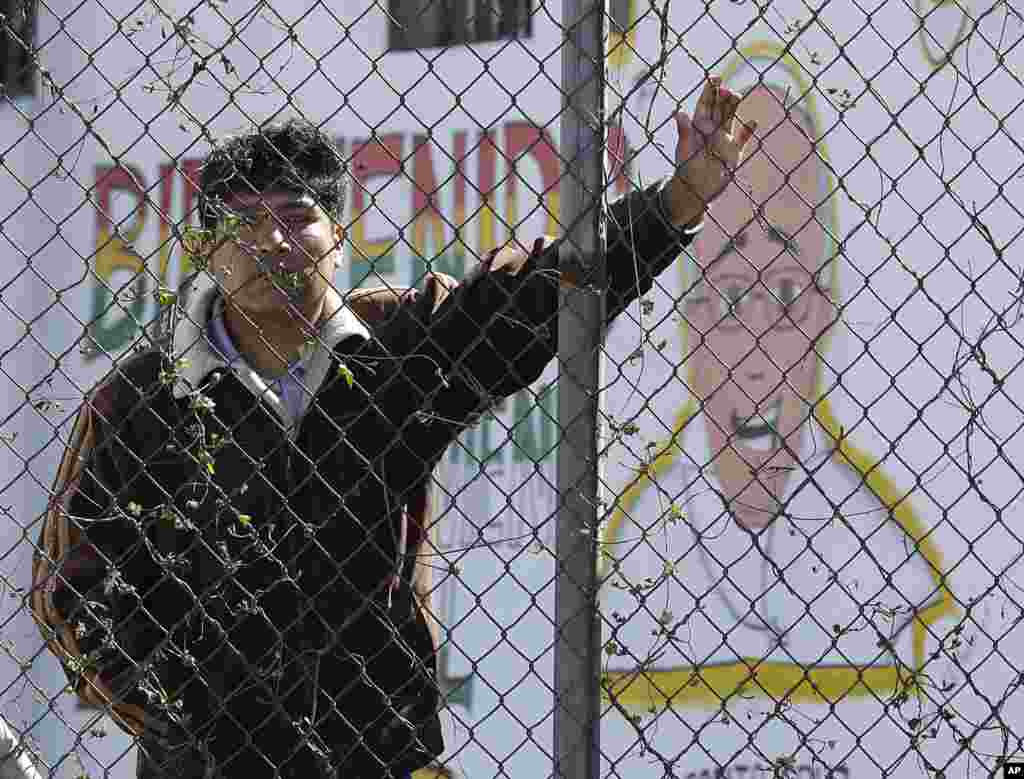 An inmate stands behind the fence at Palmasola prison, decorated with a mural of Pope Francis that reads in Spanish: "Welcome who comes in the name of the Lord" as the pontiff visited prisoners in Santa Cruz, July 10, 2015.