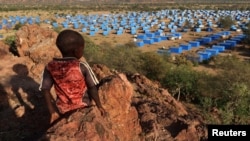 FILE - A boy sits atop a hill overlooking a refugee camp near the Chad-Sudan border, November 9, 2023. 
