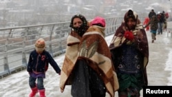 FILE - Syrian refugees brave the cold and snow as they walk to a metro station in Istanbul, February 11, 2015.