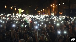 Para pengunjuk rasa mengangkat telepon selular dengan layar menyala selama rapat akbar yang diselenggarakan oleh gerakan yang disebut Freedom for Education, dengan tema CEU Now, Who’s Next-Protest for the Free Education, di depan gedung Parlemen di Budapest, Hungaria hari Minggu, 2 April 2017 (foto: Zoltan Balogh/MTI via AP)