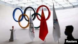 Un membre du personnel monte la garde près d'une lanterne de sécurité portant la flamme olympique des Jeux olympiques d'hiver de Pékin 2022 qui est affichée à l'intérieur de la tour olympique, à Pékin, en Chine, le 10 décembre 2021.