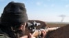 FILE- A militant fighter aims a sniper rifle during fighting in Tal Tamr, Hassakeh province, Syria, in this image posted by the Al-Baraka division of the Islamic State group, Feb. 24, 2015.