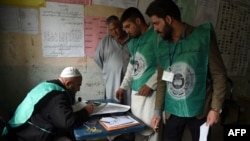This photo taken on April 14, 2018, shows Afghan employees of the Independent Election Commission registering a resident at a voter registration center for the upcoming parliamentary and district council elections in Kabul.
