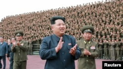 មេដឹកនាំកូរ៉េ​ខាង​ជើង​ Kim Jong Un នៅ​ក្នុង​ពេល​ថតរូប​​ជាមួយ​កង​កម្លាំង​ប្រដាប់​អាវុធ​ ដែល​ដើរ​តួ​ជា​កម្មករ​ក្នុង​ការ​សាងសង់​ផ្ទះសម្រាប់​ក្មេងៗនិង​ជន​ពិការ​ ដែល​រូបថត​នេះ​ចេញ​ផ្សាយ​ដោយ​ទីភ្នាក់ងារ​សារព័ត៌មាន​កូរ៉េខាងជើង​ កាលពីថ្ងៃទី៣ ខែមិថុនា ឆ្នាំ២០១៥។