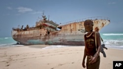 Perompak Somalia berdiri di dekat kapal nelayan yang terdampar.