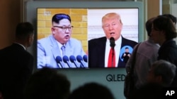 Pengunjung menyaksikan layar TV yang menunjukkan cuplikan arsip foto Presiden AS Donald Trump, kanan, dan Pemimpin Korea Utara Kim Jong Un dalam siaran berita di Stasiun Kereta Seoul di Seoul, Korea Selatan, 21 April 2018. 
