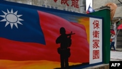 FILE - A tourist walks past a mural painted on a wall on Taiwan's Kinmen islands, which lie just 3.2 kilometers from the mainland China coast in the Taiwan Strait, Oct. 21, 2020.