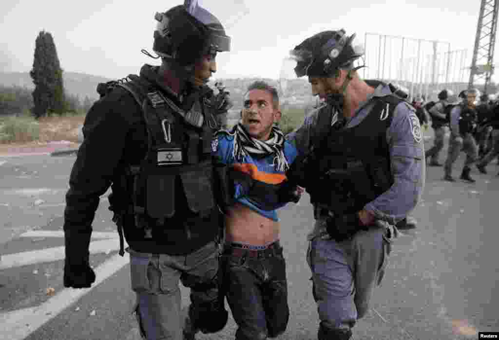 Israeli policemen detain an Arab youth during clashes at the entrance to the town of Kfar Kanna, in northern Israel, Nov. 8, 2014.