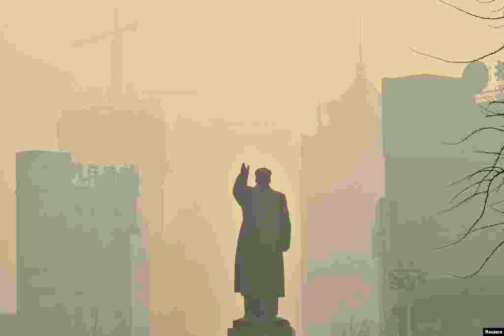 A statue of China's late Chairman Mao Zedong is seen in front of buildings during a hazy day in Shenyang, Liaoning province, May 7, 2013. 