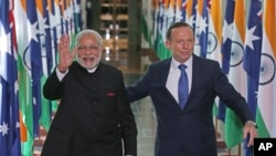 India's Prime Minister Narendra Modi, left, escorted by Australian Prime Minister Tony Abbott, waves as they leave the House of Representatives at Parliament House in Canberra, Tuesday, Nov. 18, 2014.