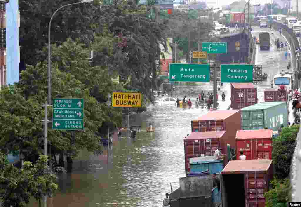 Container trucks are pictured stranded in flood waters on a road in west Jakarta January 18, 2013.