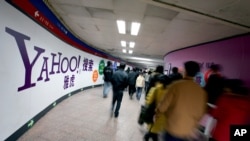 FILE - Para pengguna kereta bawah tanah China berjalan melewati iklan Yahoo di stasiun metro di Beijing.