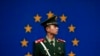 FILE - A Chinese paramilitary policeman stands on duty in front of a European Union flag outside the office of the European Union delegation to China, in Beijing, Oct. 28, 2011.