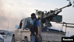 Fighters of the Islamic State of Iraq and the Levant (ISIL) stand guard at a checkpoint in the northern Iraq city of Mosul, June 11, 2014.