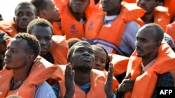 Kaum migran dan pengungsi duduk di kapal karet menanti untuk diselamatkan oleh Topaz Responder, kapal penyelamat yang dikelola oleh LSM asal Malta MOAS dan Palang Merah Italia, tanggal 4 November 2016, lepas pantai Libya (foto: AFP PHOTO/Andreas Solaro)