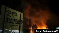 "RIP Rayshard" terlihat pada sebuah papan ketika api menelan restoran Wendy selama protes Sabtu, 13 Juni 2020, di Atlanta. (Foto: AP/Brynn Anderson)